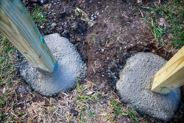 Wooden fence post in hole with concrete